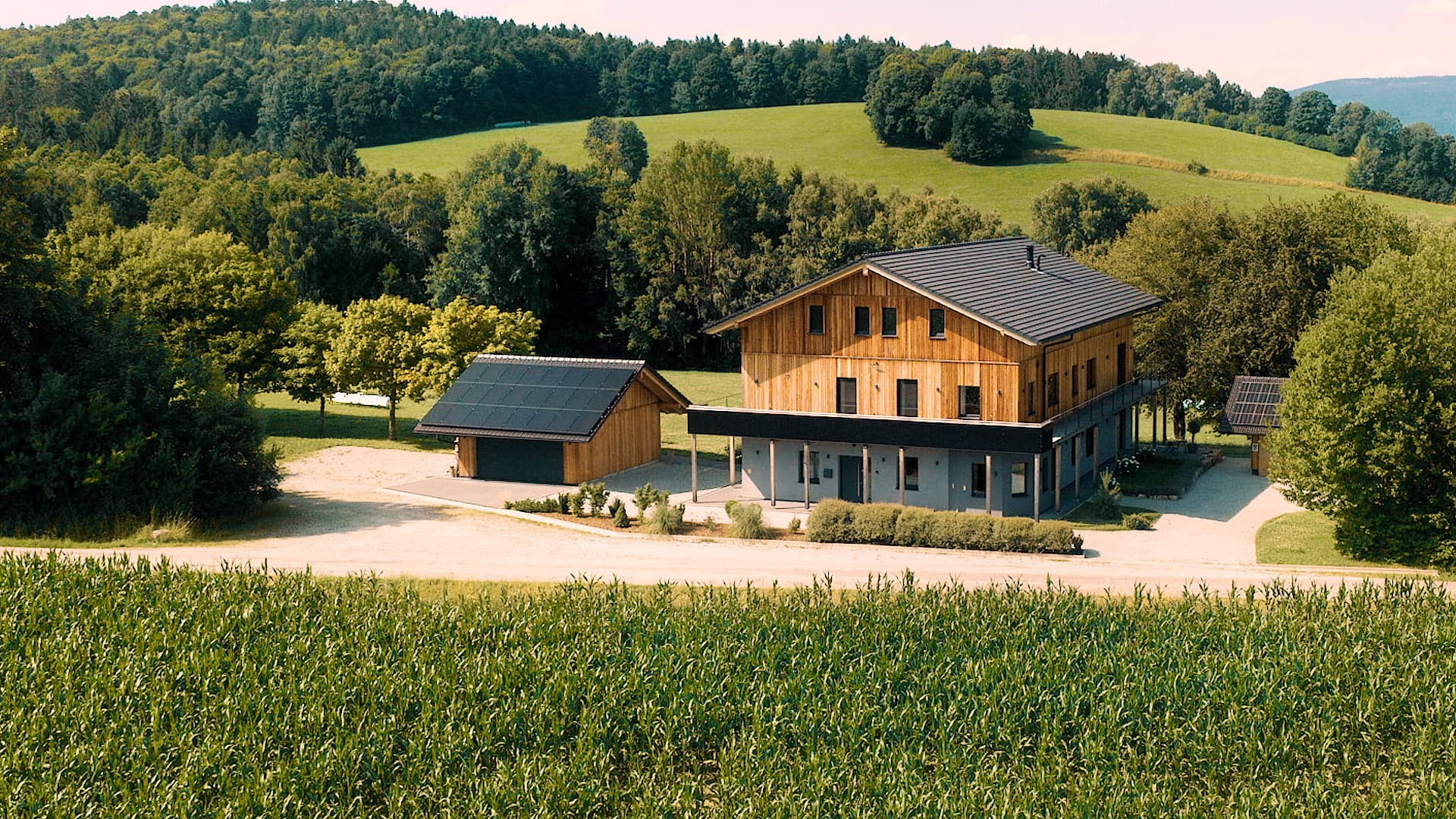 Das Traumhaus im Bayersichen Wald mit grünen Hügeln und Wald im Hintergrund