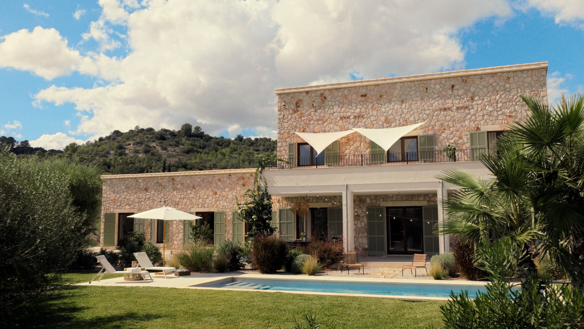 Das Traumhaus auf Mallorca in der Gartenansicht mit Blick auf den Pool und der überdachten Terrasse.