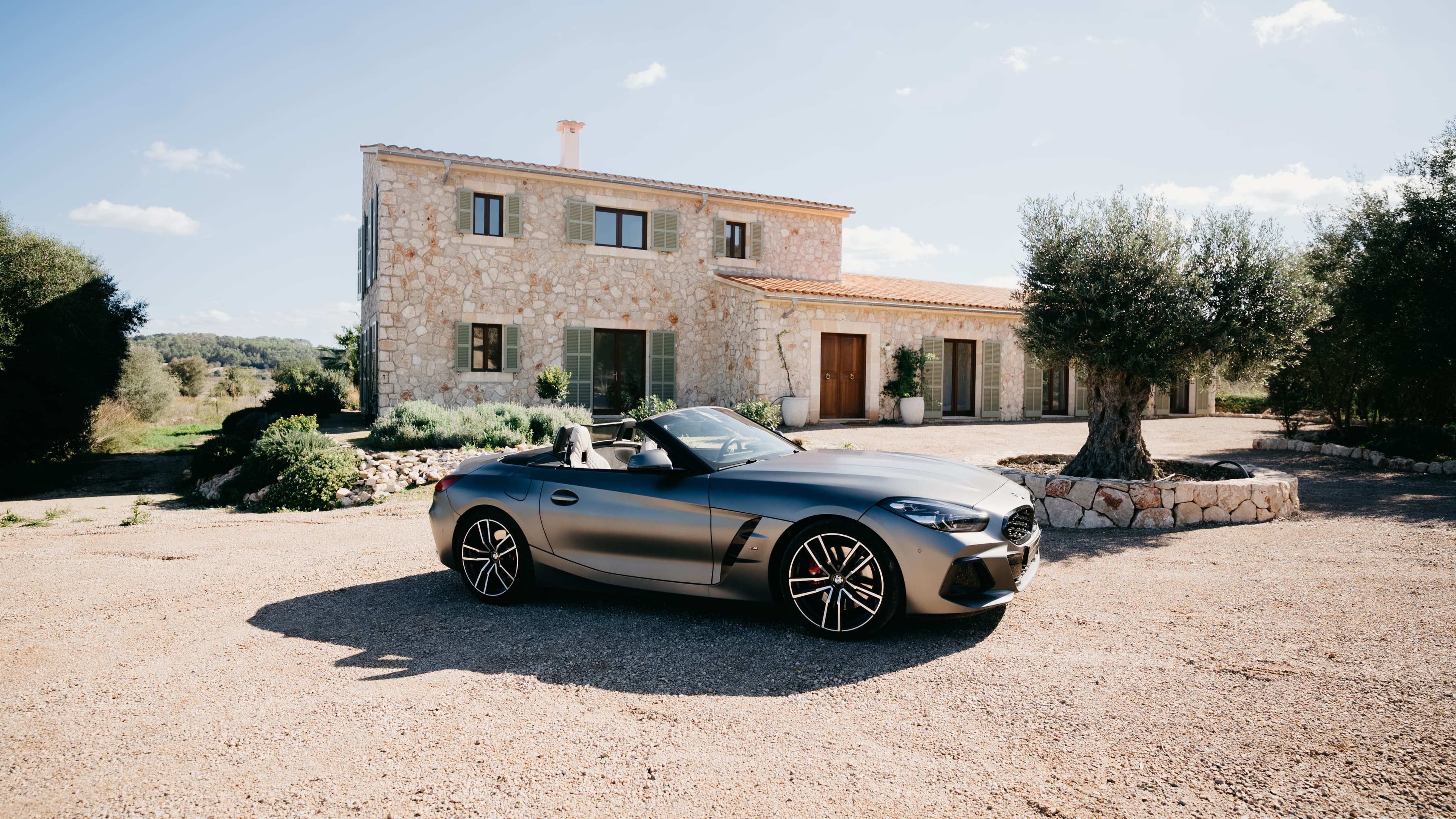 Ein BMW Z4 in silber steht seitlich vor dem Traumhaus auf Mallorca