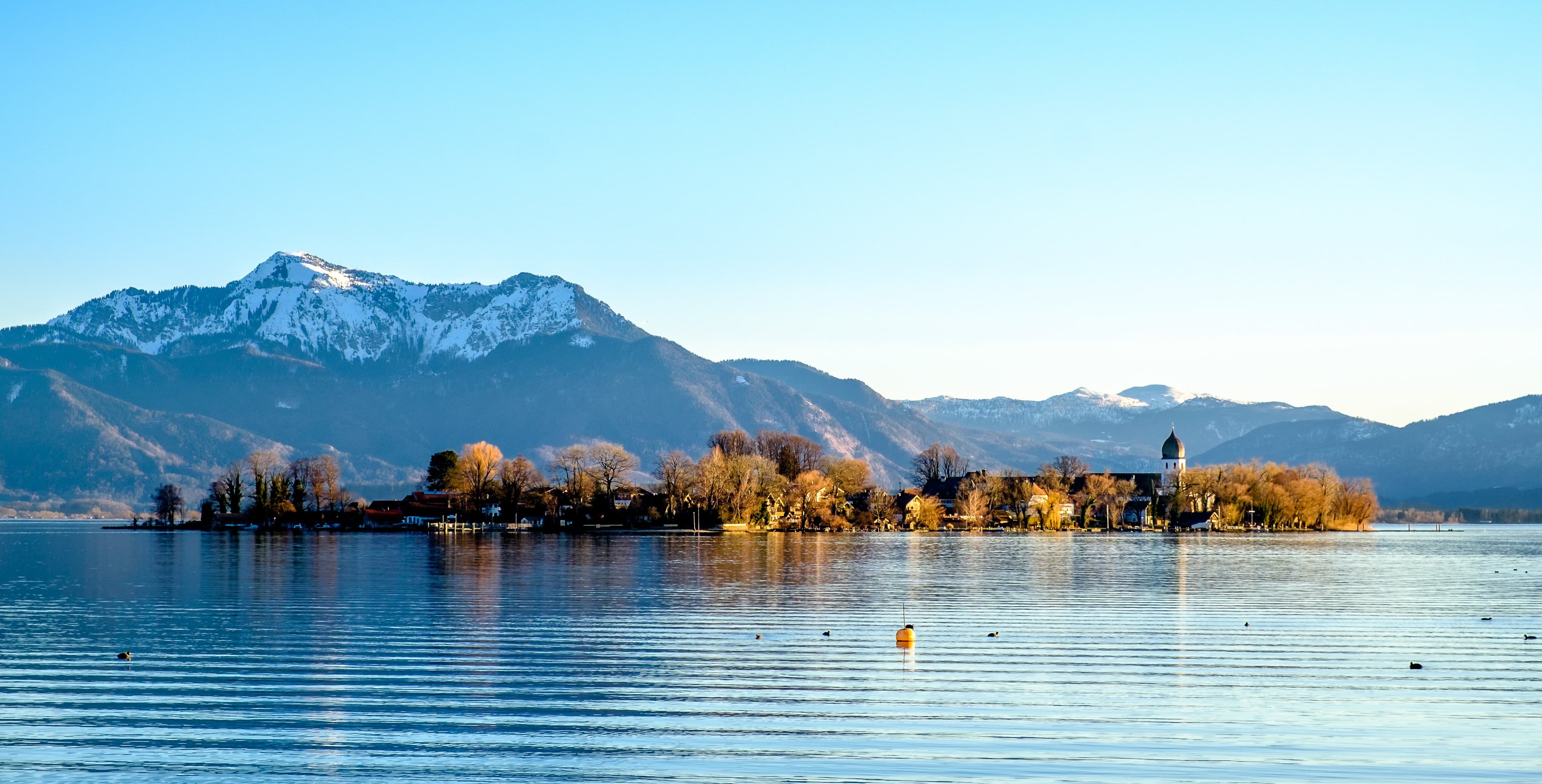 Der Chiemsee mit Blick auf die Fraueninsel und den Bergen im Hintergrund