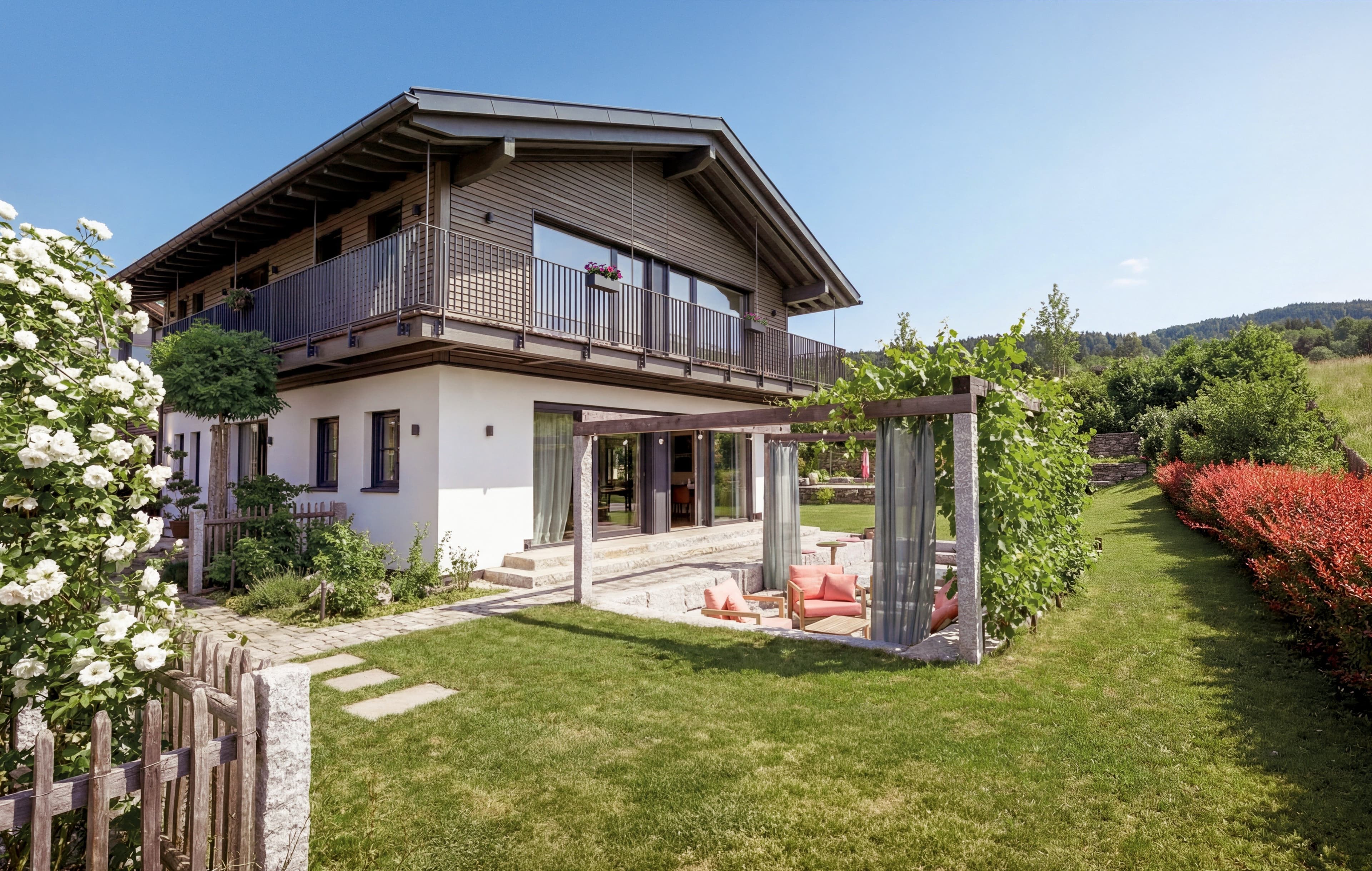 Blick auf das Traumhaus am Chiemsee und den Garten mit Feuerstelle und Sitzgelegenheiten