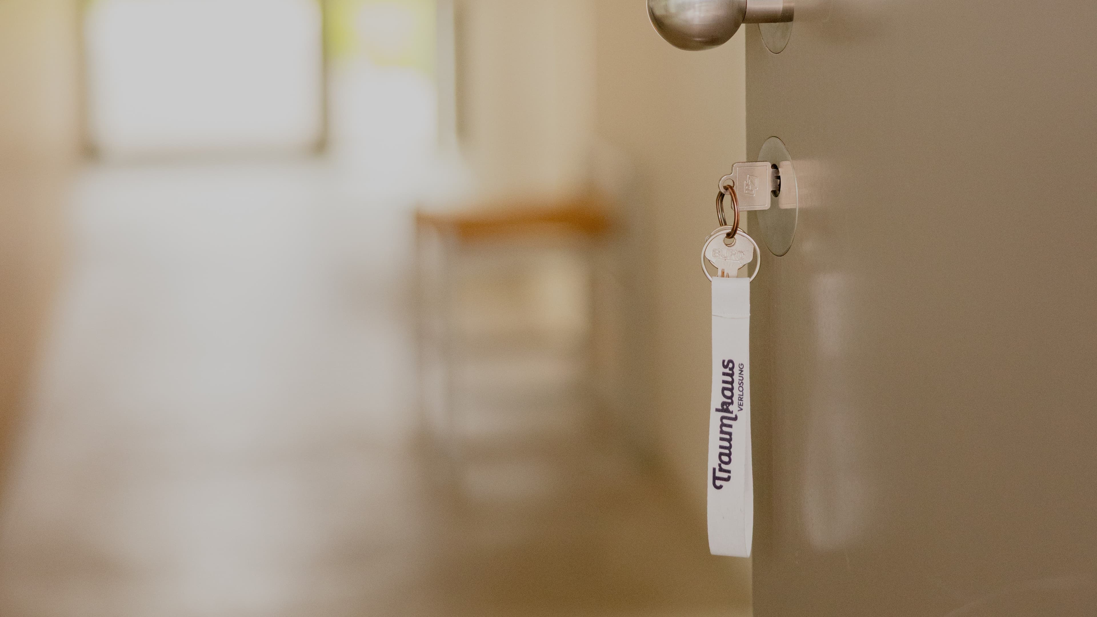 Offene Eingangstür mit einem Schlüssel an dem ein Traumhausverlosungs-Schlüsselband hängt