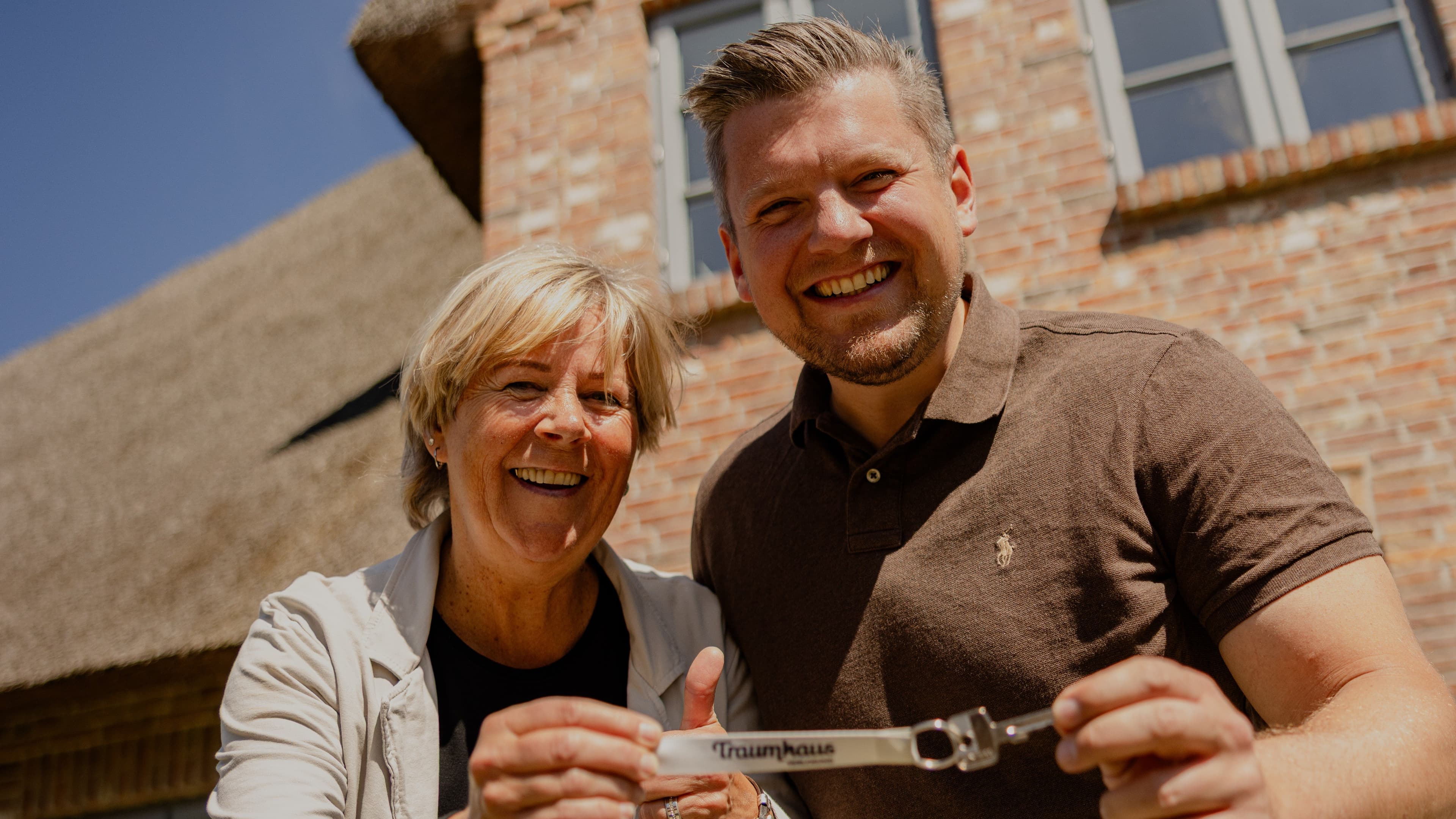 Birgit und ihr Sohn halten voller Freude den Schlüssel vom Traumhaus auf Föhr in die Kamera