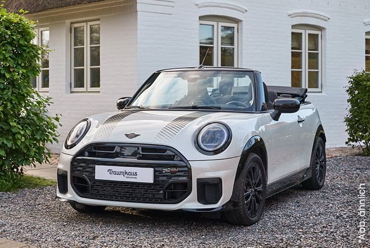 Weißes Mini Cooper Cabrio mit schwarzen Details von vorne fotografiert, direkt vor dem Traumhaus auf Amrum